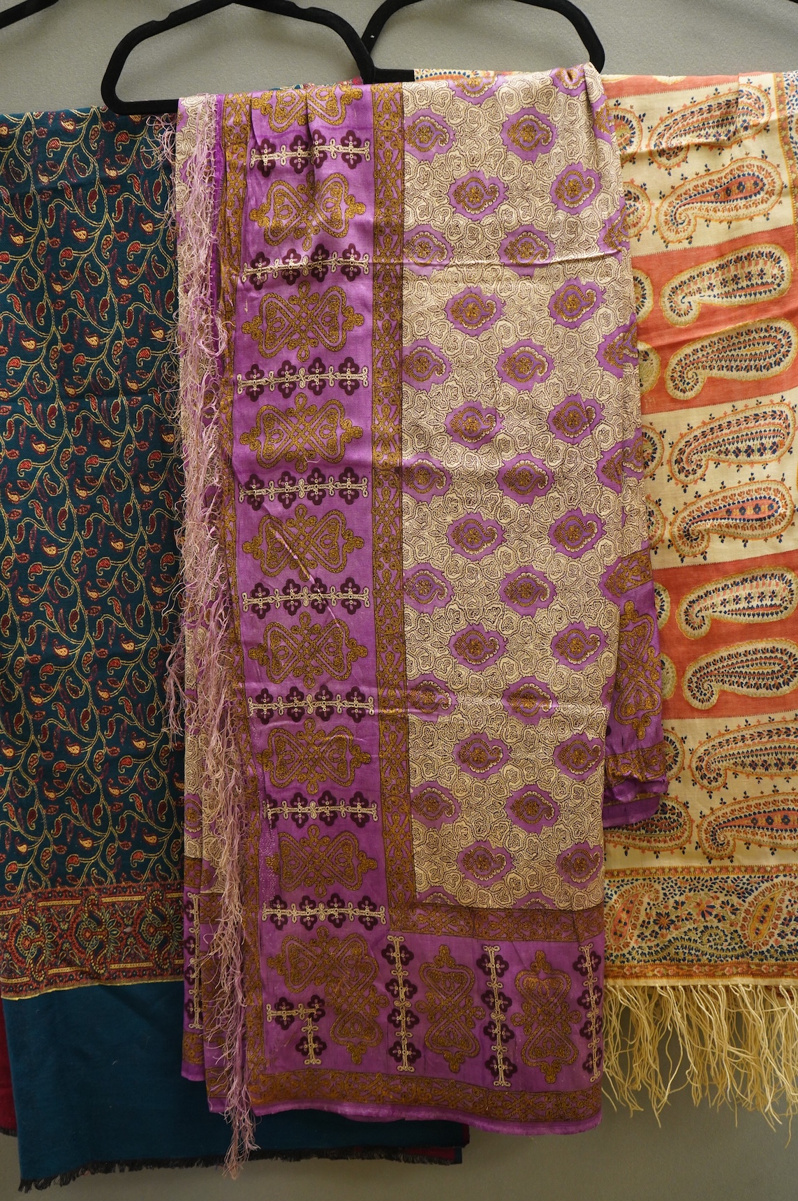 A 19th century printed silk shawl and a printed paisley shawl, together with a late 20th century wool machine woven stole with Oswal label. Condition - the two 19th century shawls are damaged but useful for TV and film c